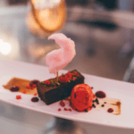 Exquisite dessert featuring rich chocolate and topped with pink candy floss, served on a beautifully plated dish for an elegant dining experience.