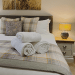 A cosy bed with a countryside feel, dressed in luxurious Egyptian cotton bedding and neatly folded towels, creating a serene and inviting atmosphere.